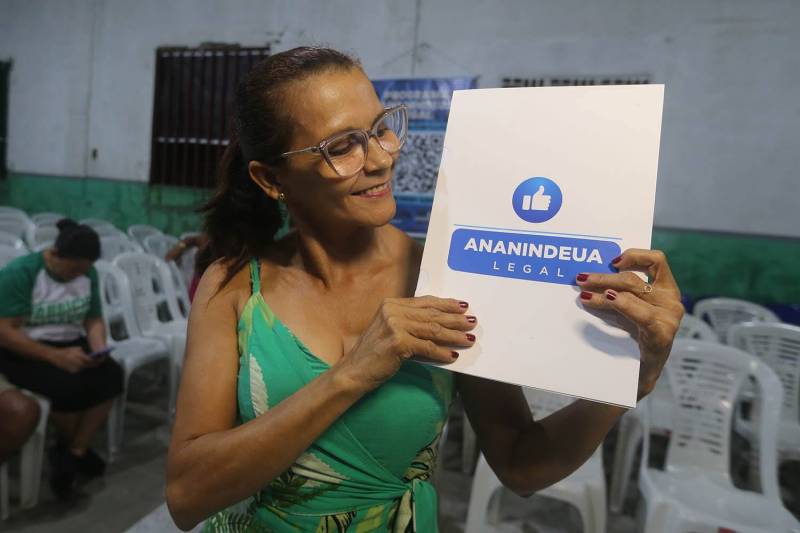 Moradora comemora o recebimento do título.